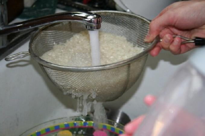 Sperite riž v cedilo udobno s tekočo vodo.